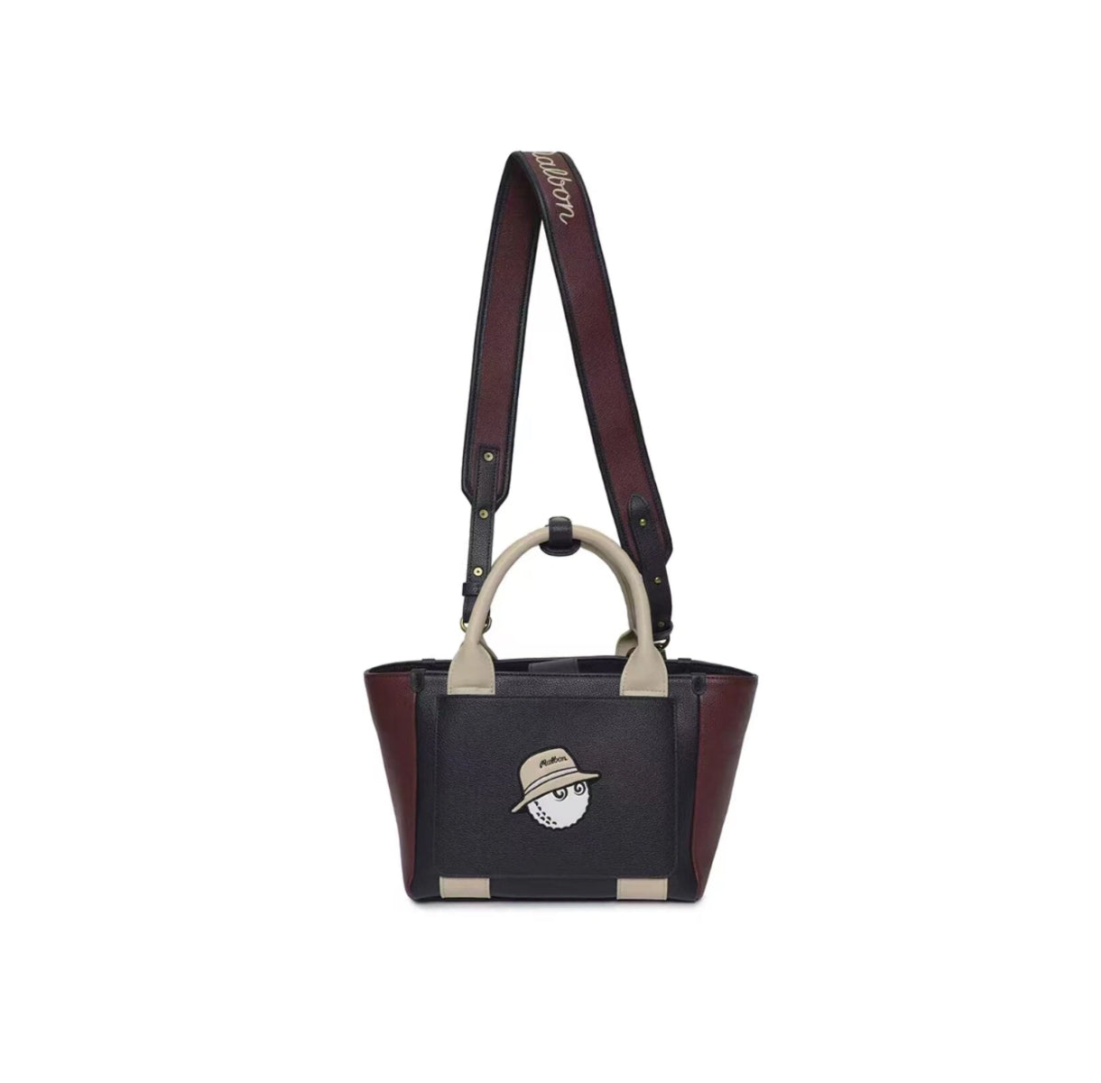 Front view of the Malbon Clubhouse mini tote bag in black and burgundy leather-like material featuring a playful golf ball mascot wearing a hat with "Malbon" text. Vintage-inspired design with top handles and adjustable shoulder strap.