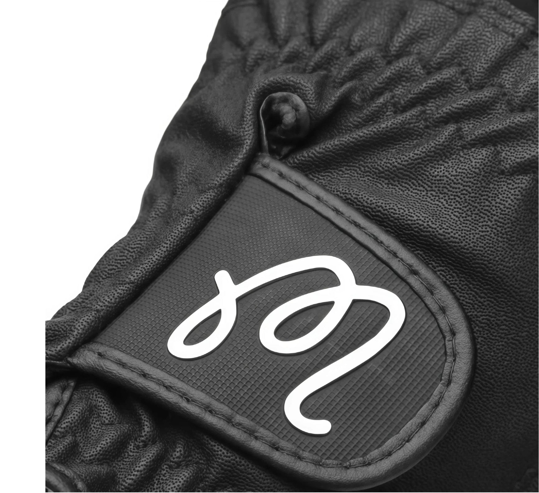 Close-up of Malbon golf glove logo on black wrist strap, showing embossed design and high-quality stitching, emphasizing brand identity and premium craftsmanship.