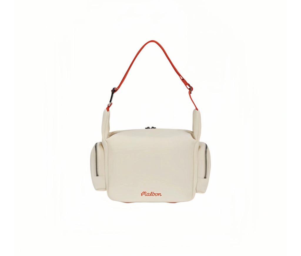 Front view of Malbon Golf small shoulder bag in cream showing minimalist red "Malbon" embroidery at bottom center, dual side zip pockets, and orange adjustable crossbody strap