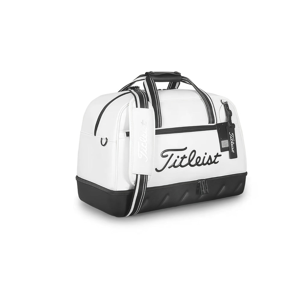 Three-quarter front view of the white Titleist Boston Bag with black "Titleist" script logo, branded shoulder strap, and textured base. Premium golf duffel for men and women.